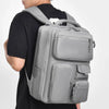 A person is wearing a gray travel backpack with a laptop compartment on their back.