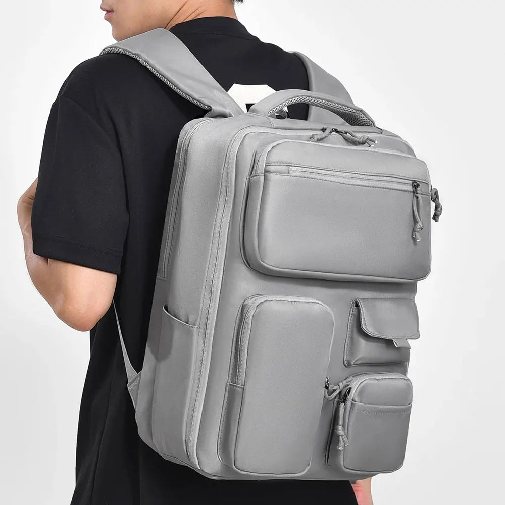 A person is wearing a gray travel backpack with a laptop compartment on their back.