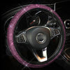 A close-up of a black steering wheel covered in sparkling pink crystal rhinestones.