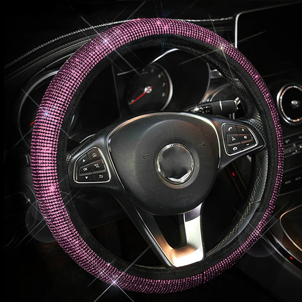 A close-up of a black steering wheel covered in sparkling pink crystal rhinestones.