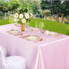 A pink satin tablecloth set for a formal outdoor dining event with floral decorations and glassware.