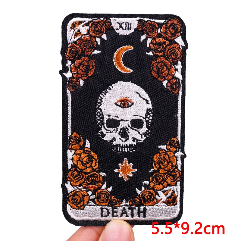 Black embroidered patch featuring a skull and crescent moon surrounded by orange roses with iron-on backing