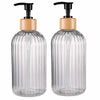 A pair of clear glass refillable soap dispensers with wooden caps and black pump tops.