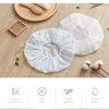 White waterproof shower cap for bathing and hair care shown on a wooden surface.