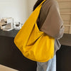 A person is holding a bright yellow lightweight nylon tote bag with a secure zipper closure.