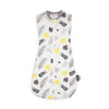A white baby sleep sack featuring a pattern of green and yellow leaves on a gray fabric.