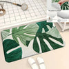 A rectangular non-slip area rug featuring a tropical green leaf print on a white background.