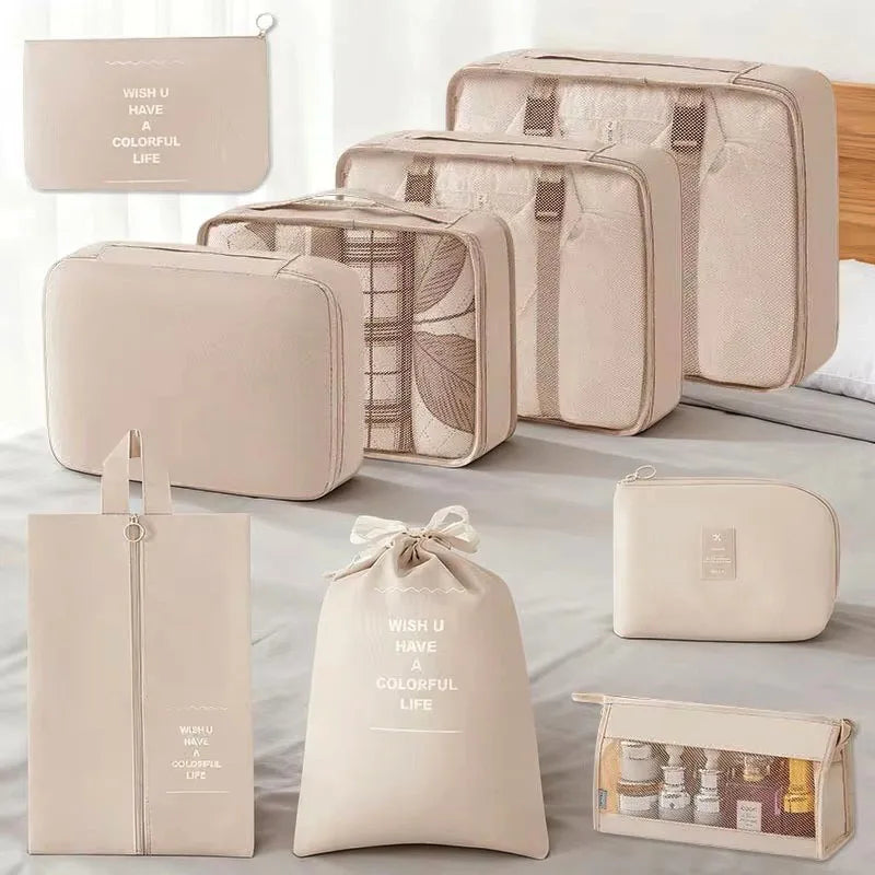 A set of beige and cream travel packing cubes and storage organizer bags displayed on a white surface.