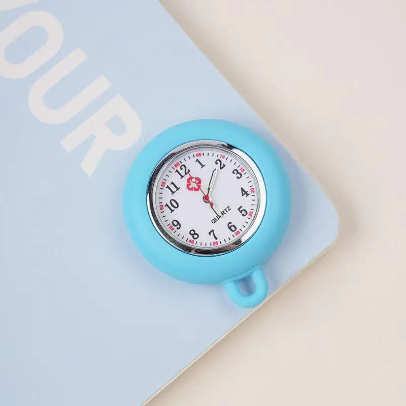 A light blue silicone pocket watch with a white face and black hands is shown on a pale background.