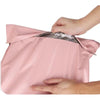 A hand is opening a pink waterproof poly mailer shipping bag to reveal the contents.