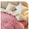 A pink quilted velvet duvet cover and blanket displayed on a bed.