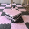Pink and gray interlocking floor tiles with a pink fluffy mat and a black decorative object.