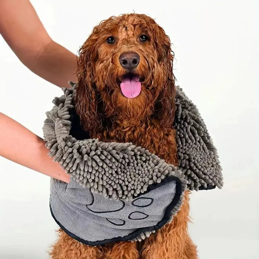 A golden retriever is wearing a gray pet bath towel while being held by a person.