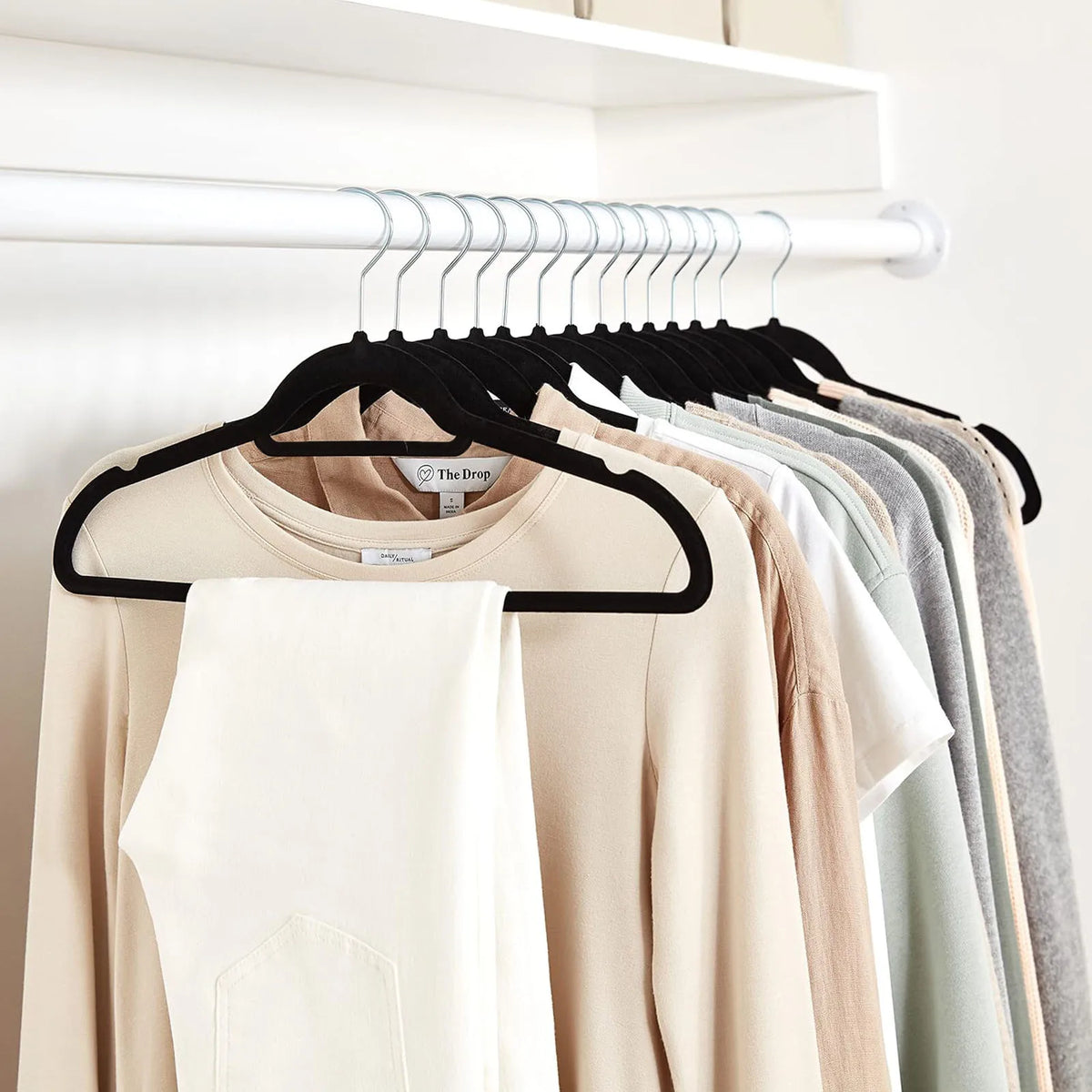 A rack of black velvet hangers displaying various colored t-shirts and tops.