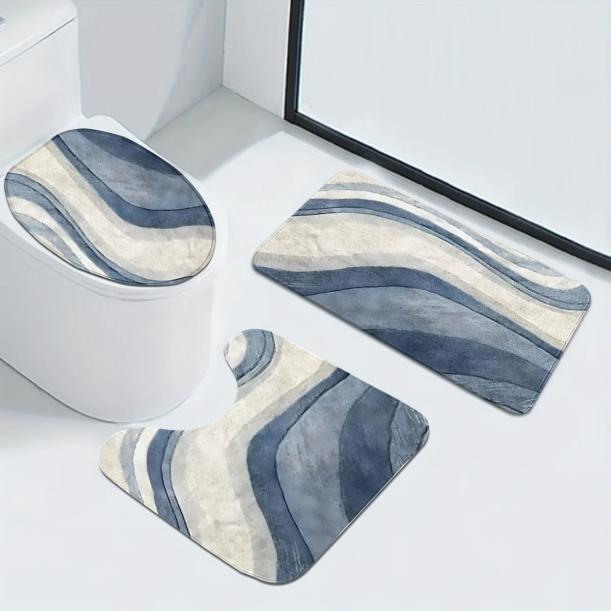 A set of three striped bathroom rugs, including a U-shaped toilet mat and cover, displayed on a white surface.
