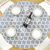 A gray round tablecloth set for a meal with silverware and wine on a wooden table.