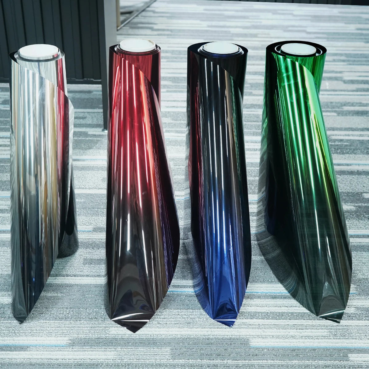 Four vertical strips of gradient car window tint film showing a spectrum of colors from red to green and blue.