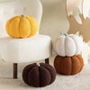 A collection of soft, fluffy decorative pumpkins in yellow, white, and brown fabric cushions.
