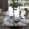 A marble-patterned dining table with gold veining, set for a meal, in a modern room.
