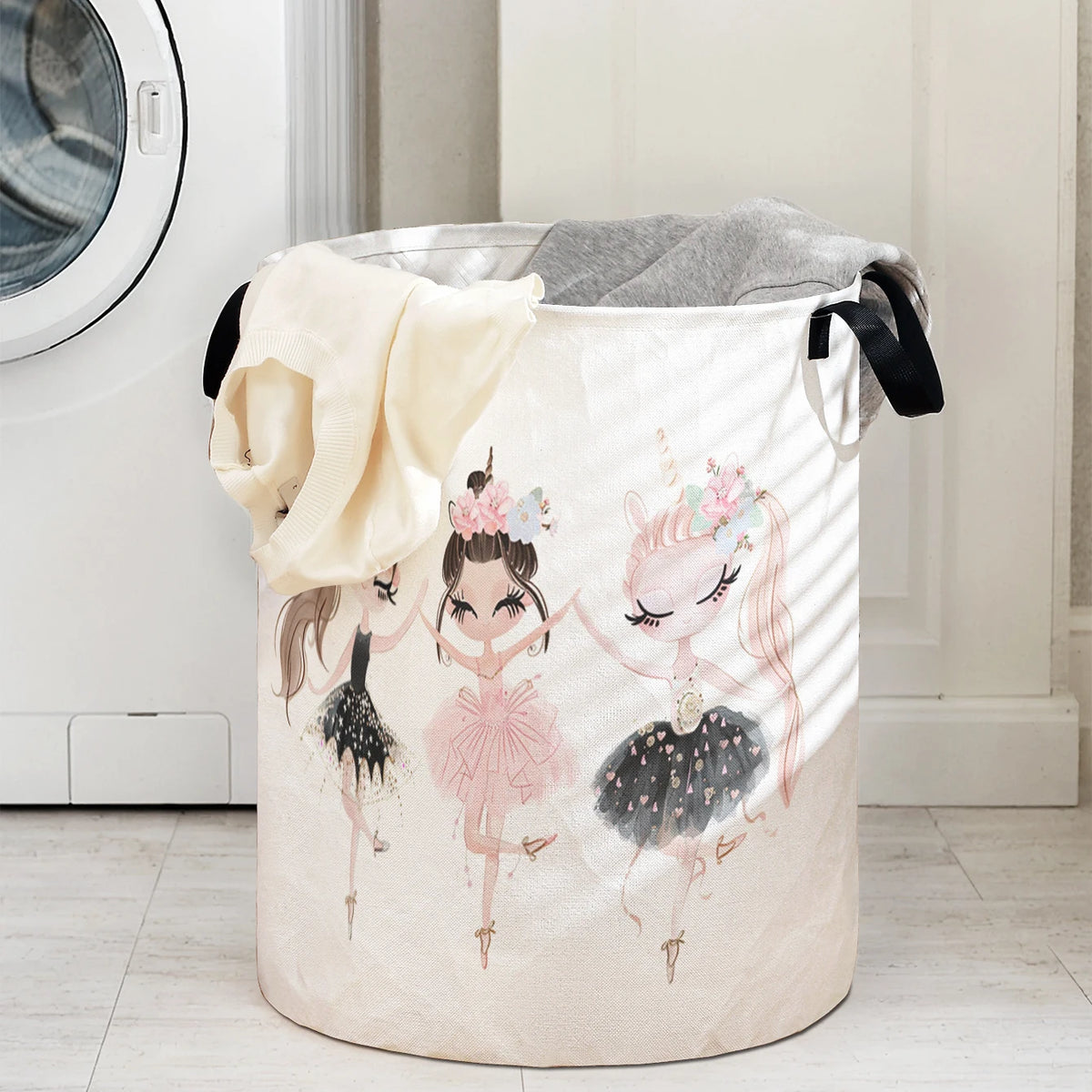 A beige storage basket with a unicorn ballerina print and black handles.