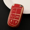 A red and gold durable TPU car key case cover resting on a black surface next to a white dish.
