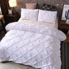 White quilted comforter and pillowcases set displayed on a bed with decorative pillows.