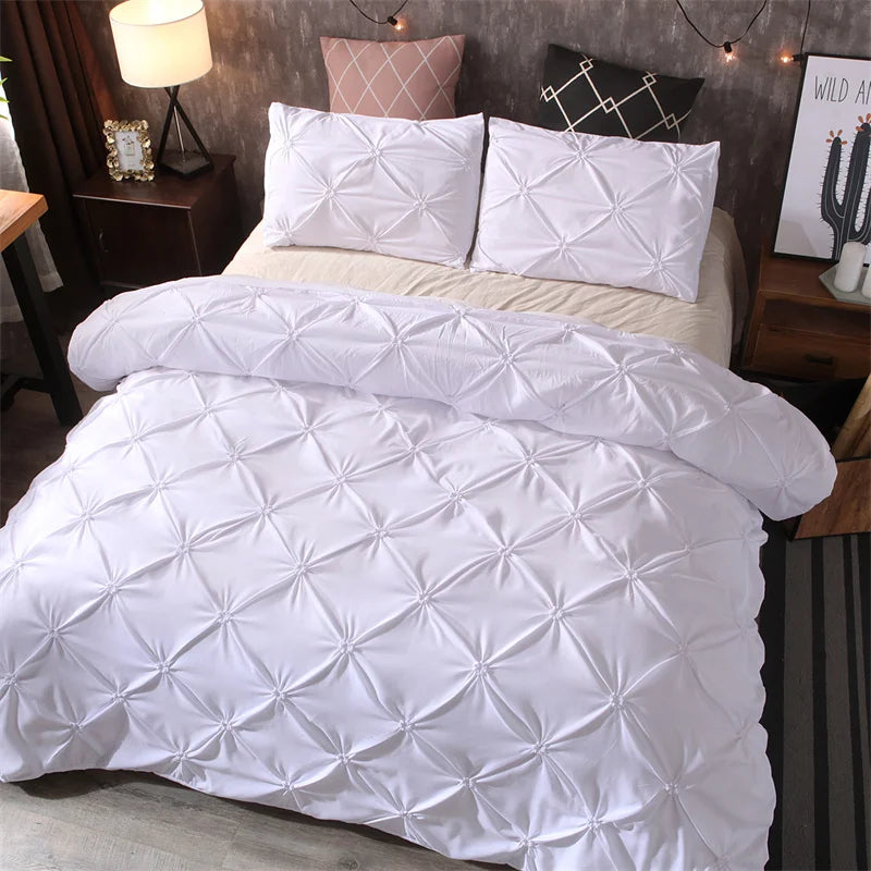 White quilted comforter and pillowcases set displayed on a bed with decorative pillows.