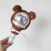 A brown plush bear head with a clear dome and pink ribbon attached to a light stick cover.