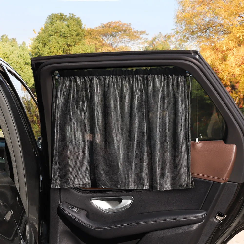 A black car window is covered with a black sunshade inside the vehicle.