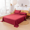 A deep red bedding set featuring a fitted sheet, flat sheet, and pillowcases displayed on a bed in a bright room.