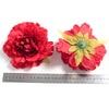 Two vibrant red silk peony flower heads with yellow centers displayed next to a ruler.
