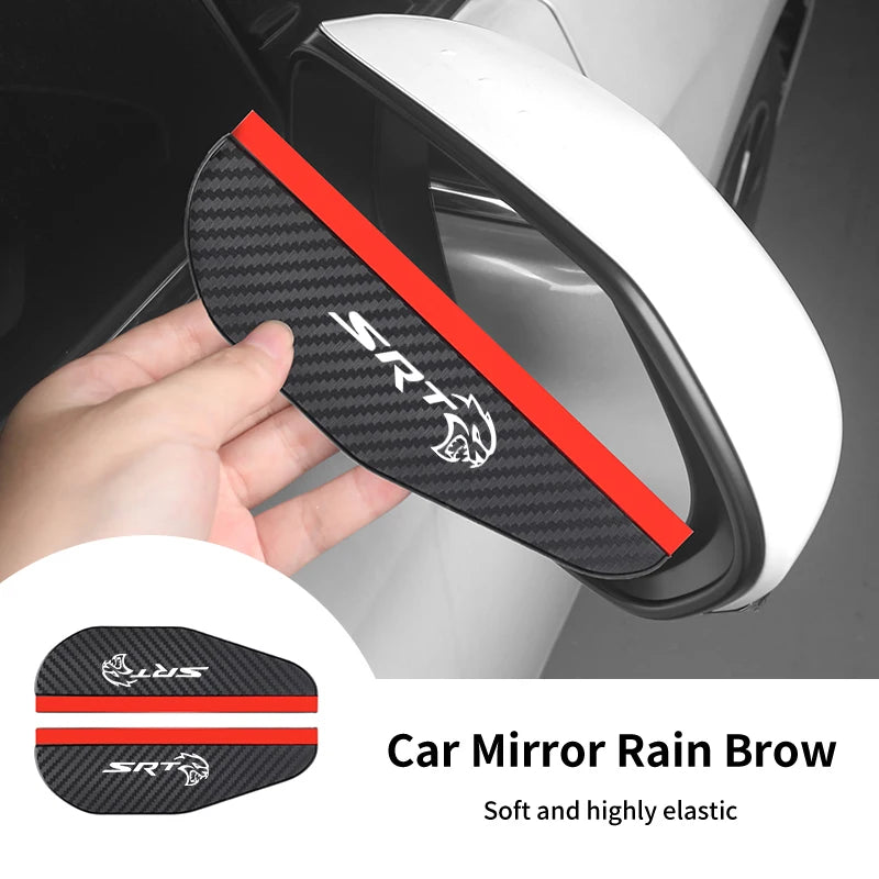 A hand holds a black carbon fiber rain brow for a car mirror, designed to improve visibility.