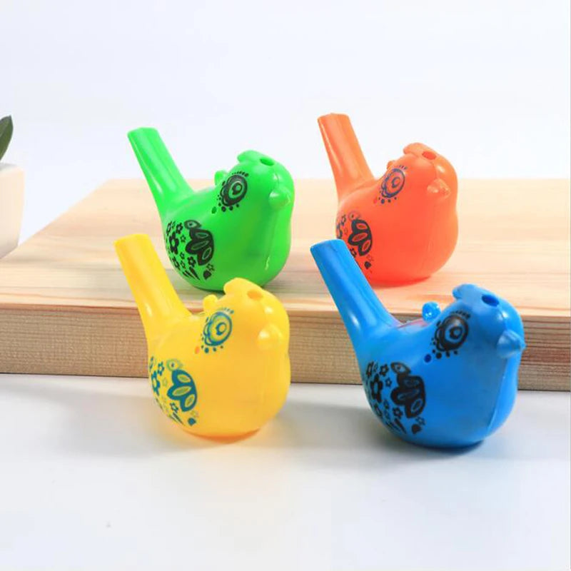 Three plastic bird whistles in green, orange, and blue are displayed on a wooden surface.