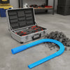 A silver storage box containing dryer vent cleaning tools and a blue flexible vacuum hose on a gray floor.