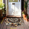 A circular doormat made of various natural stone tiles placed on a wooden floor in front of a white door.