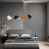 A modern bedroom featuring a bed with gray linens, accented by a wall with vertical wood grain wallpaper and decorative light