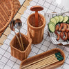 A collection of handwoven wicker serving baskets and wooden chopsticks displayed on a white grid surface.