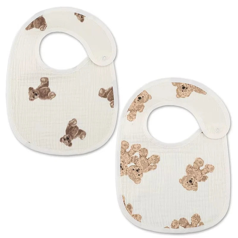 A pair of white baby cotton gauze bibs with a subtle beige pattern and waterproof backing.