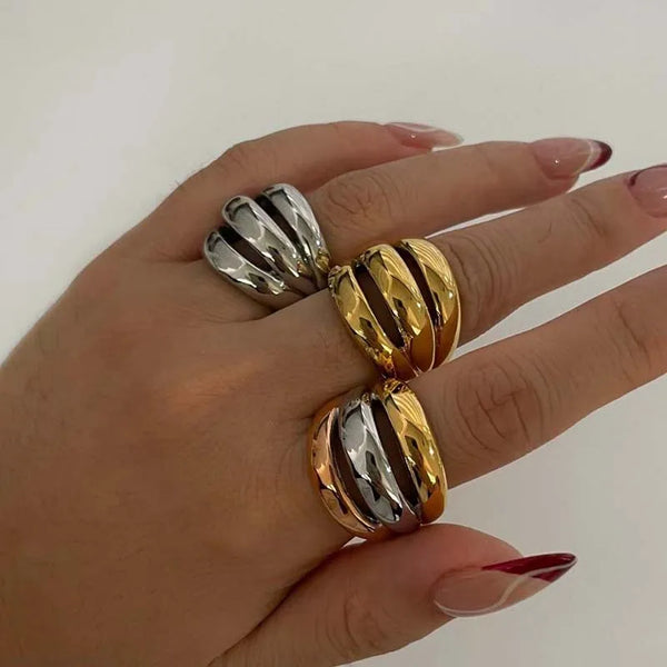 A hand wearing a chunky multi-tone dome ring featuring alternating silver and gold stripes.