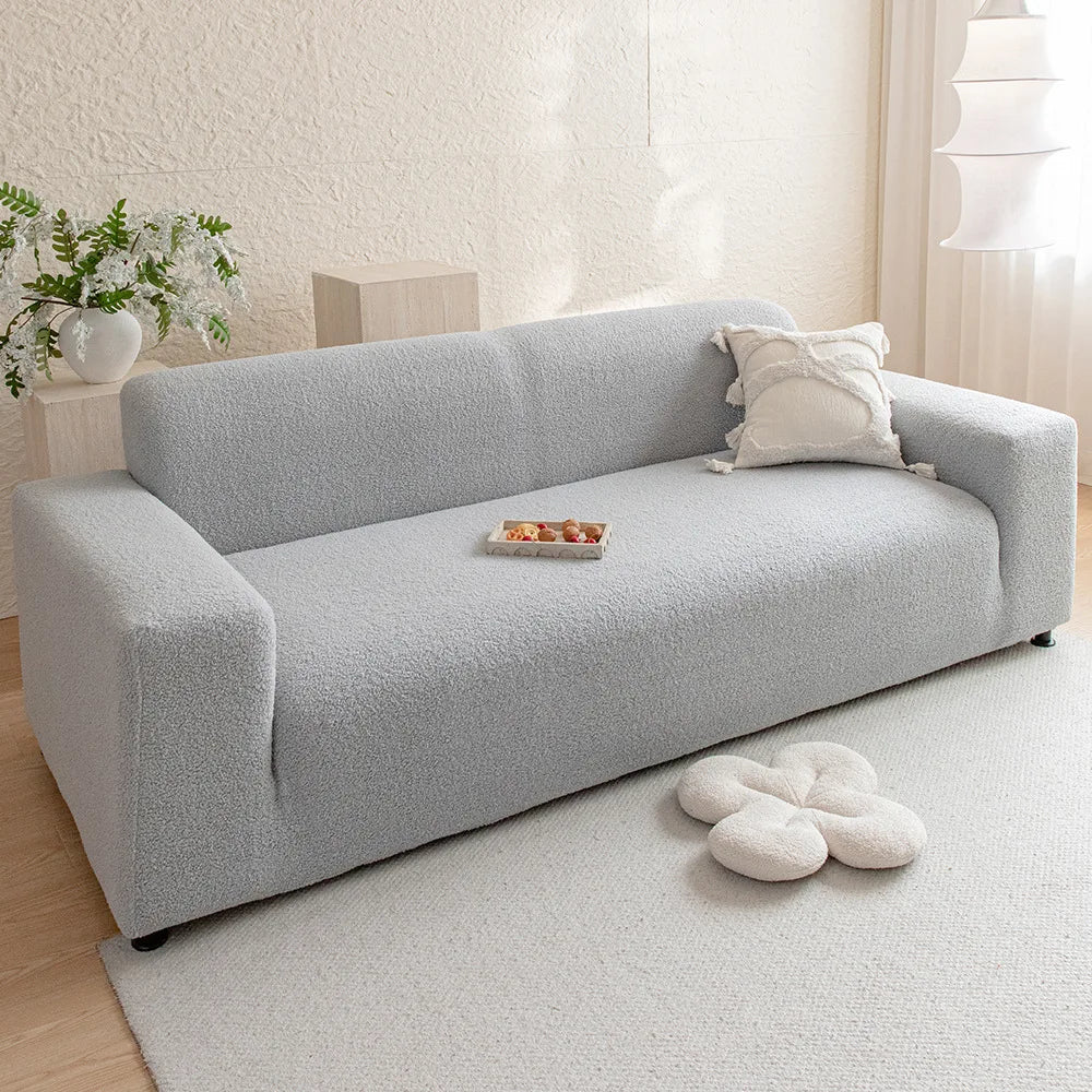A light gray plush sofa cover with a white cushion and decorative pillows on a modern living room floor.