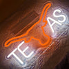 Orange cow head neon sign with the letters TEAS illuminated on a textured surface.