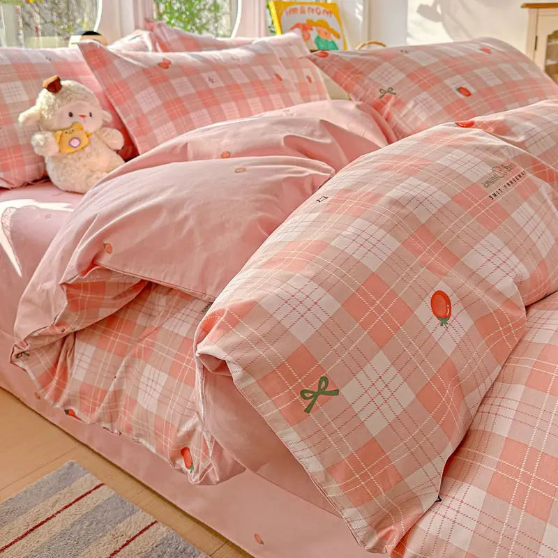 Pink plaid duvet cover set with matching pillow shams and a small stuffed animal on a bed.