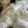 A luxurious white ruffled duvet cover set with matching pillowcases and a book on a bed.