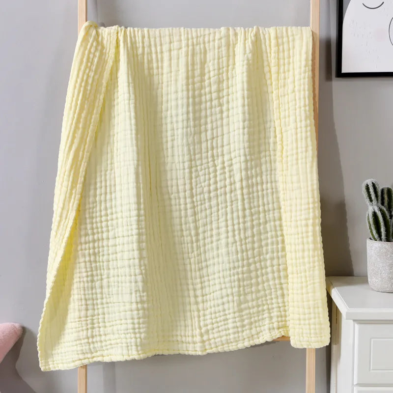 A yellow, textured muslin cotton blanket hanging on a wooden rack.
