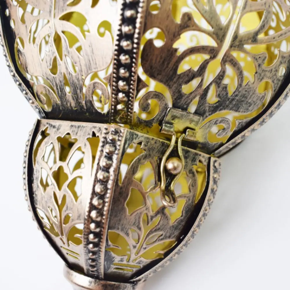 A close-up of a decorative metal solar hollow-out lantern with intricate cutout patterns.