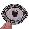 Black embroidered patch with white text and a heart design that reads We need never be ashamed of our tears