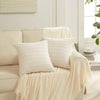 A close-up of a cream and white reversible corduroy pillowcase with a striped velvet design resting on a light-colored sofa.