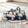 A set of baby diaper bags and accessories featuring navy blue and beige patterns on a white fluffy rug.