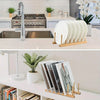 A wooden bamboo dish drying rack holding several white plates on a kitchen counter.