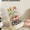 A clear rotating display case holds various small collectible figures and keepsakes on a light-colored surface.